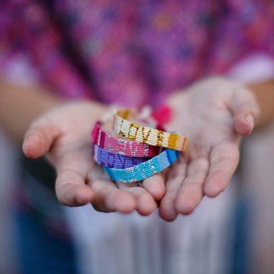 An artisan holds a stack of Atitlan LOVE Bracelets from Love Is Project