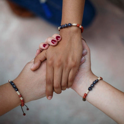 Three girls holding hands wearing the Achira Harmony LOVE Bracelet - Love Is Project