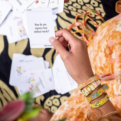 A model holding the Spread the Love Deck of Cards and wearing the Aloha Sky Bali Friendship Bracelet from Love Is Project