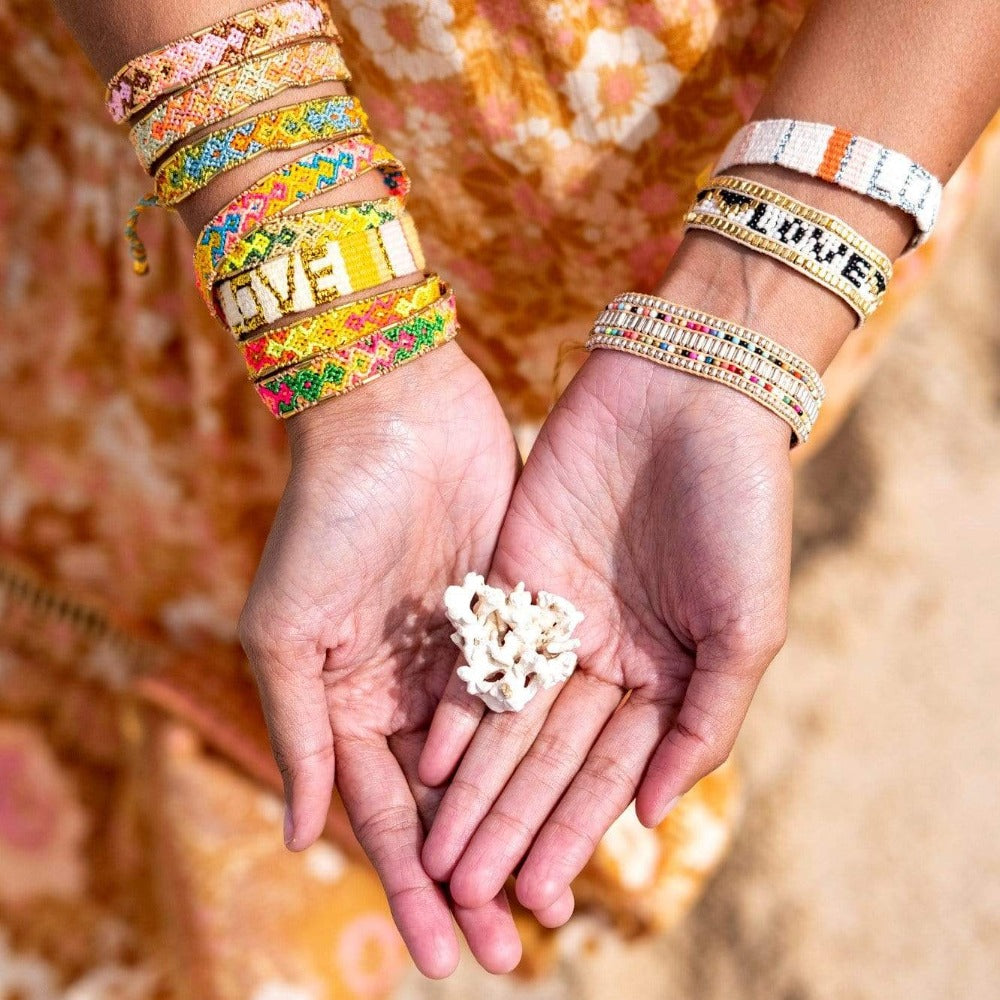 Models wearing stacks of the Jungle Bloom Bali Friendship Bracelets from Love Is Project