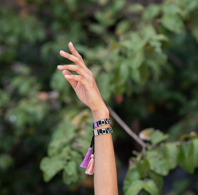 A model wearing the Black and Coral Atitlan LOVE Bracelet from Love Is Project