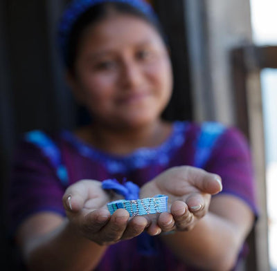 An artisan holds a Blue, Turquoise, and Indigo Atitlan LOVE Bracelet from Love Is Project