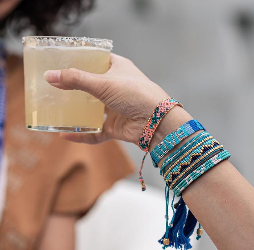 A model holding a drink and wearing the Canyon Sun Bali Friendship Bracelet