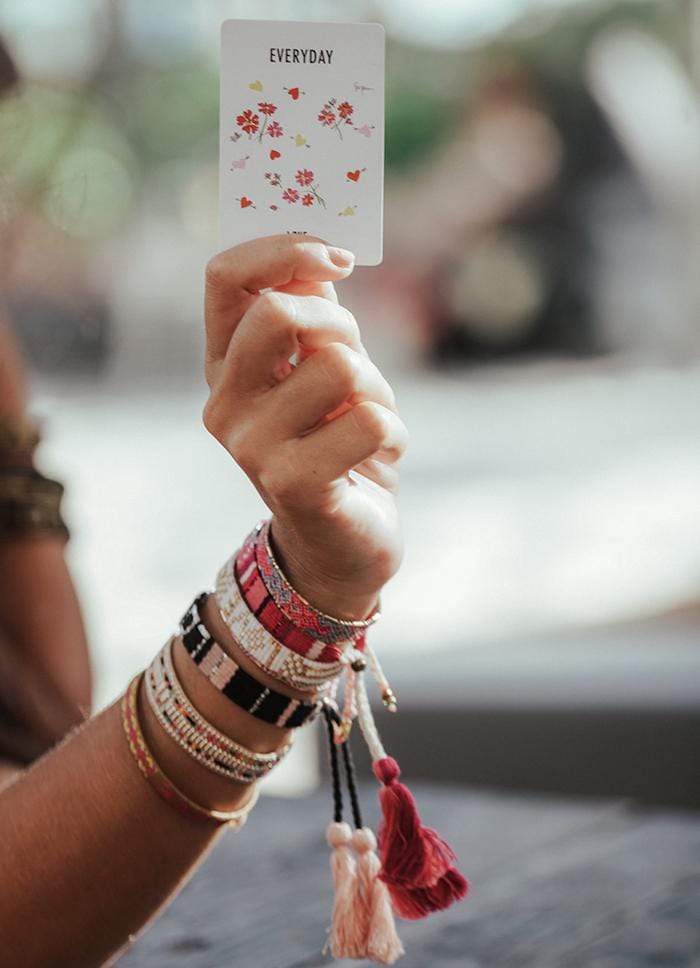 A model holding our Spread the Love Deck of Cards and wearing the Canyon Spring Bali Friendship Bracelet from Love Is Project